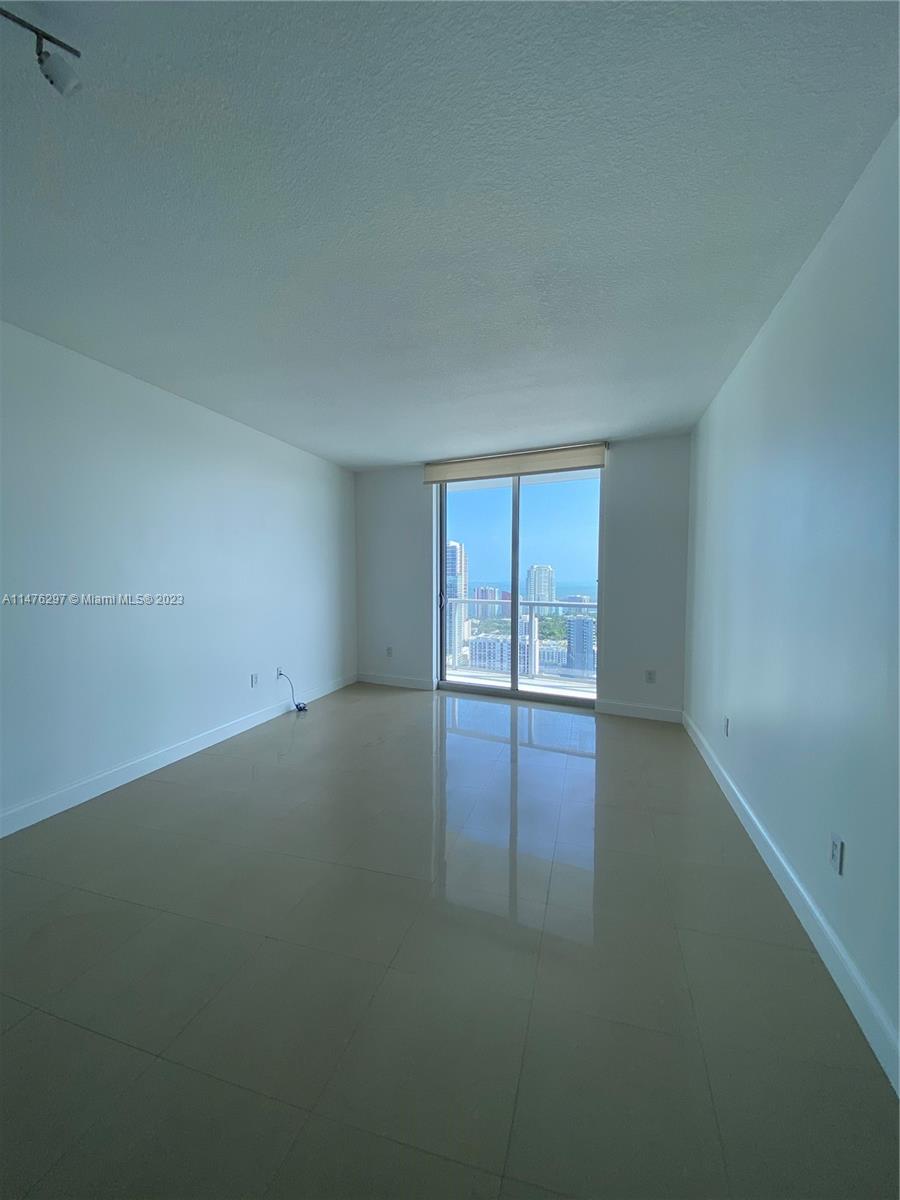 185 Southwest 7th Street, Unit 4110 Miami, FL 33130 - Photo 3 of 14 an empty room with wooden floor and windows