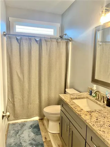 a bathroom with a granite countertop sink toilet and a mirror