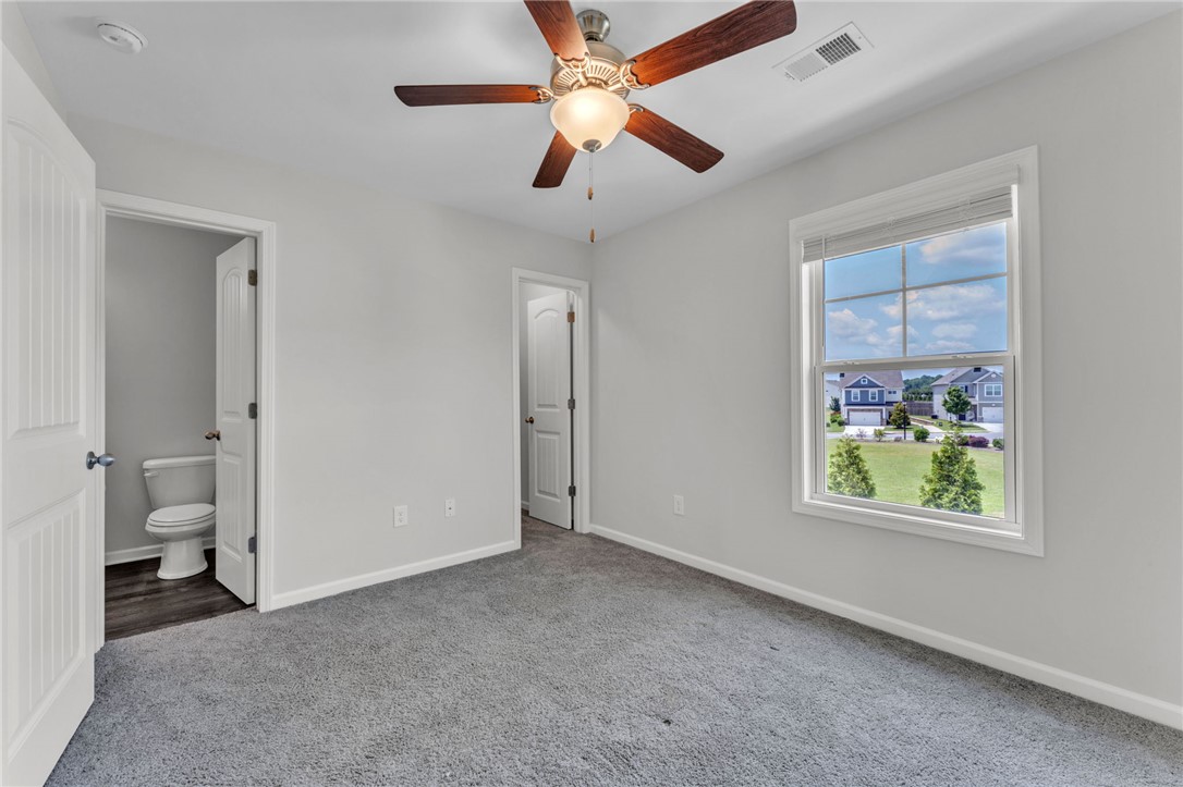 208 Samuel Street Pendleton, SC 29670 - Photo 16 of 32 A quiet secondary bedroom offers serene neighborhood views and a refreshing ceiling fan.