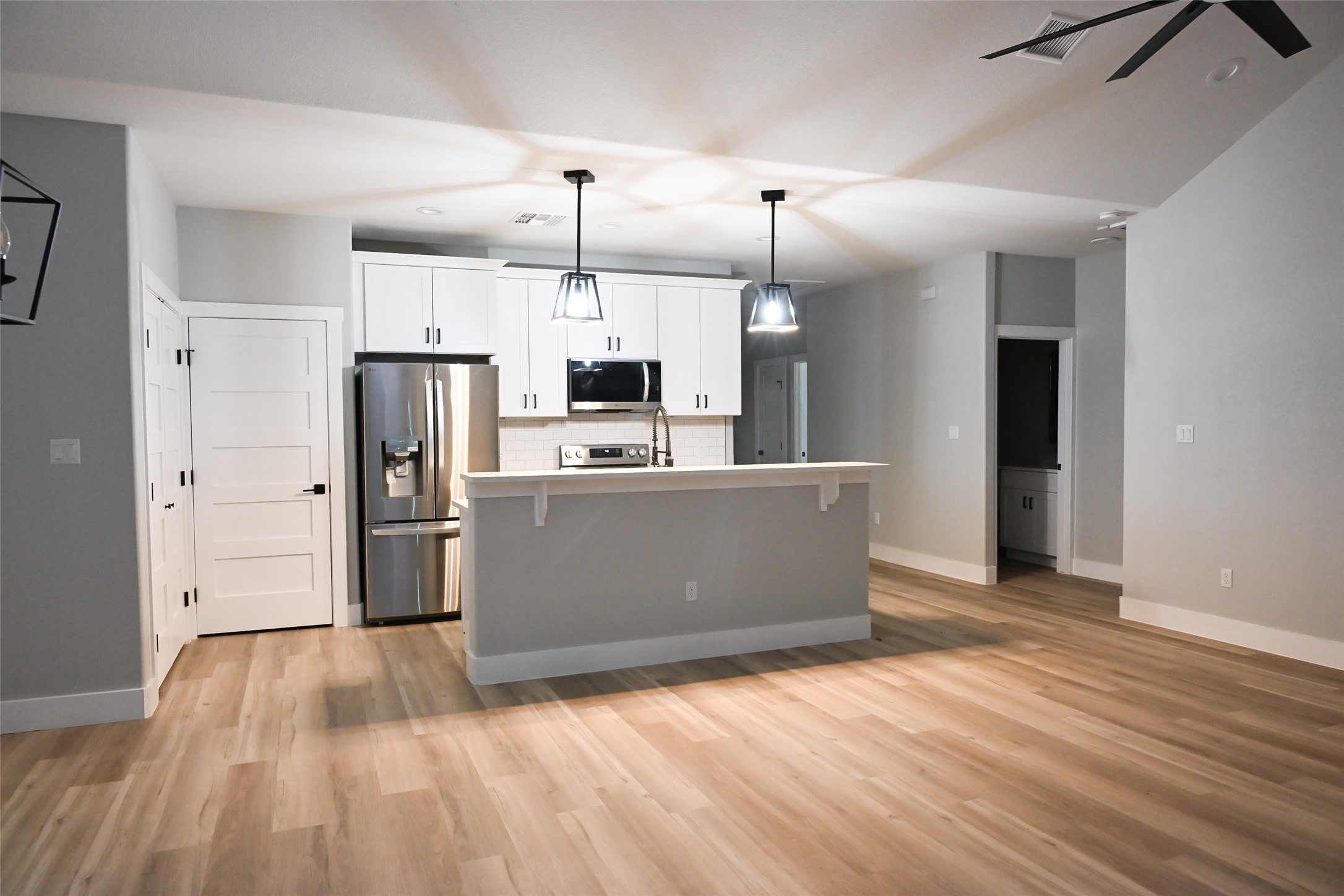 516 North Hackberry Avenue Luling, TX 78648 - Photo 23 of 36 Kitchen featuring stainless steel appliances, white cabinets, light countertops, hanging light fixtures, and a kitchen island with sink