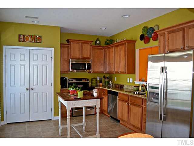1364 Regulator Street Raleigh, NC 27603 - Photo 10 of 24 a kitchen with stainless steel appliances kitchen island granite countertop a refrigerator and wooden cabinets