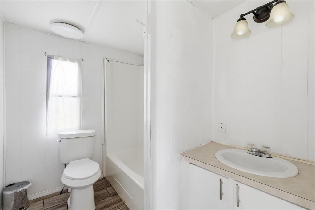 316 Summit Drive Springtown, TX 76082 - Photo 16 of 39 Well-lit bathroom featuring a window, toilet, bathtub, and vanity with an oval sink