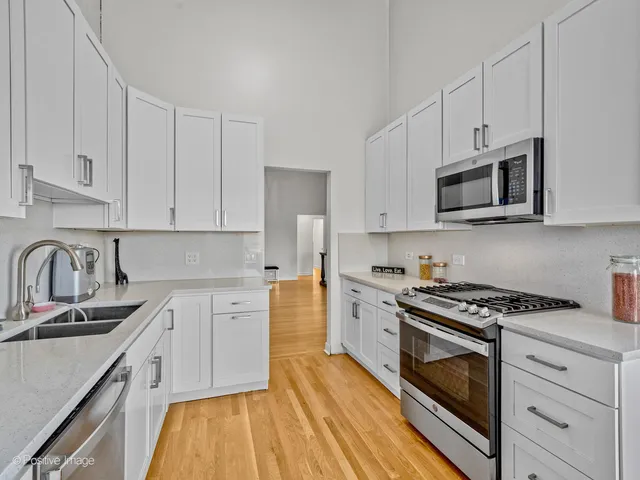 a kitchen with stainless steel appliances granite countertop white cabinets granite counter tops and a hard wood floors