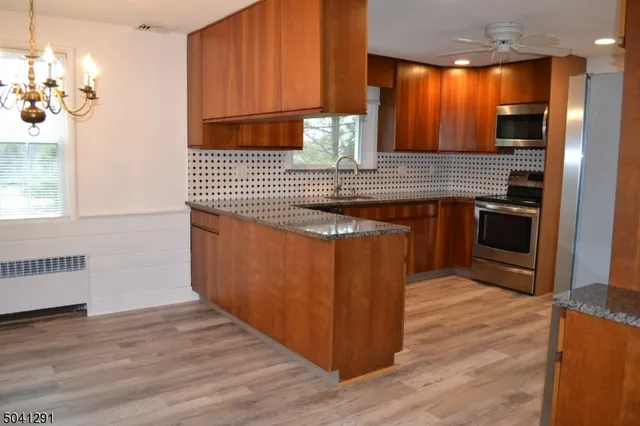 a kitchen with stainless steel appliances granite countertop a sink a stove and a wooden floor