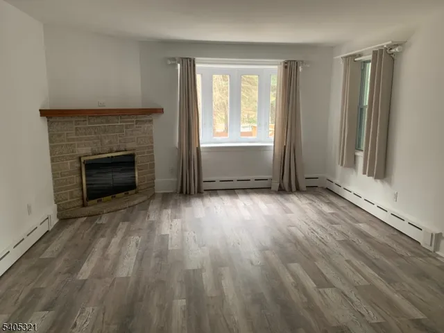 an empty room with wooden floor fireplace and windows