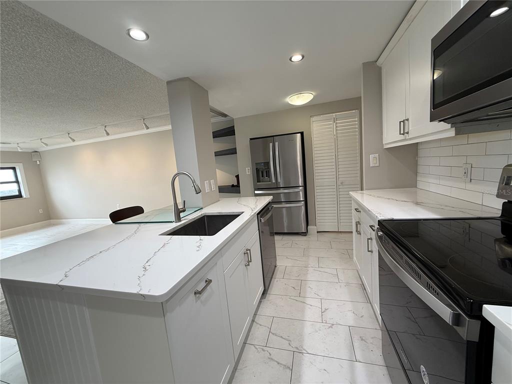 4141 Bayshore Boulevard, Unit 1203 Tampa, FL 33611 - Photo 2 of 16 a kitchen with stainless steel appliances a sink stove and refrigerator