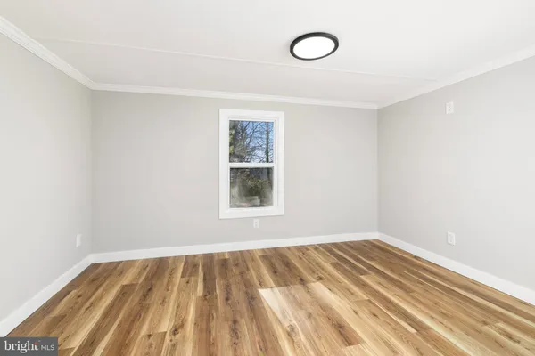 a view of an empty room with wooden floor and window
