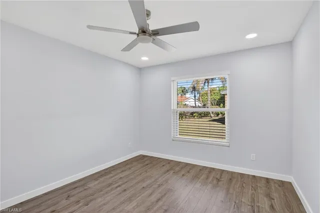an empty room with wooden floor ceiling fan and windows
