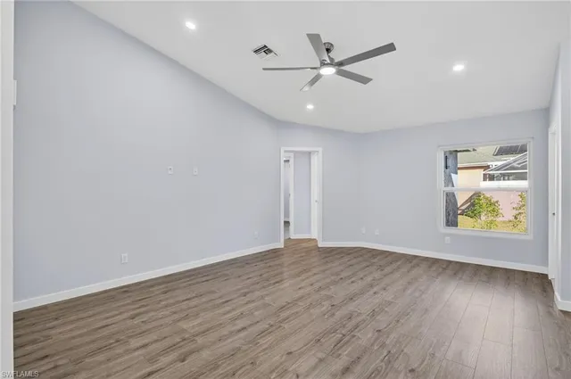 a view of an empty room with a window and wooden floor