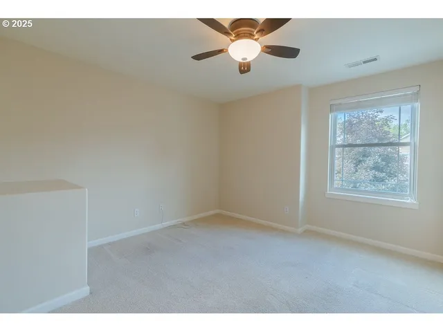 an empty room with a window and a fan