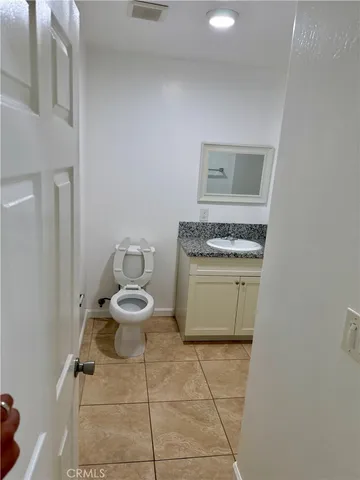 a bathroom with a granite countertop toilet sink and mirror