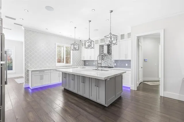 a kitchen with kitchen island granite countertop wooden floors and white cabinets