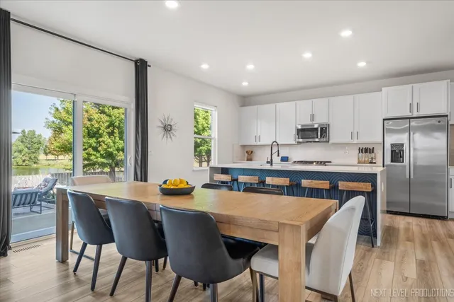 a kitchen with stainless steel appliances granite countertop a stove a refrigerator a sink a stove and white cabinets with wooden floor