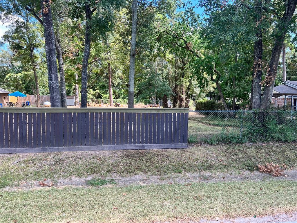a view of a backyard with large trees and wooden fence