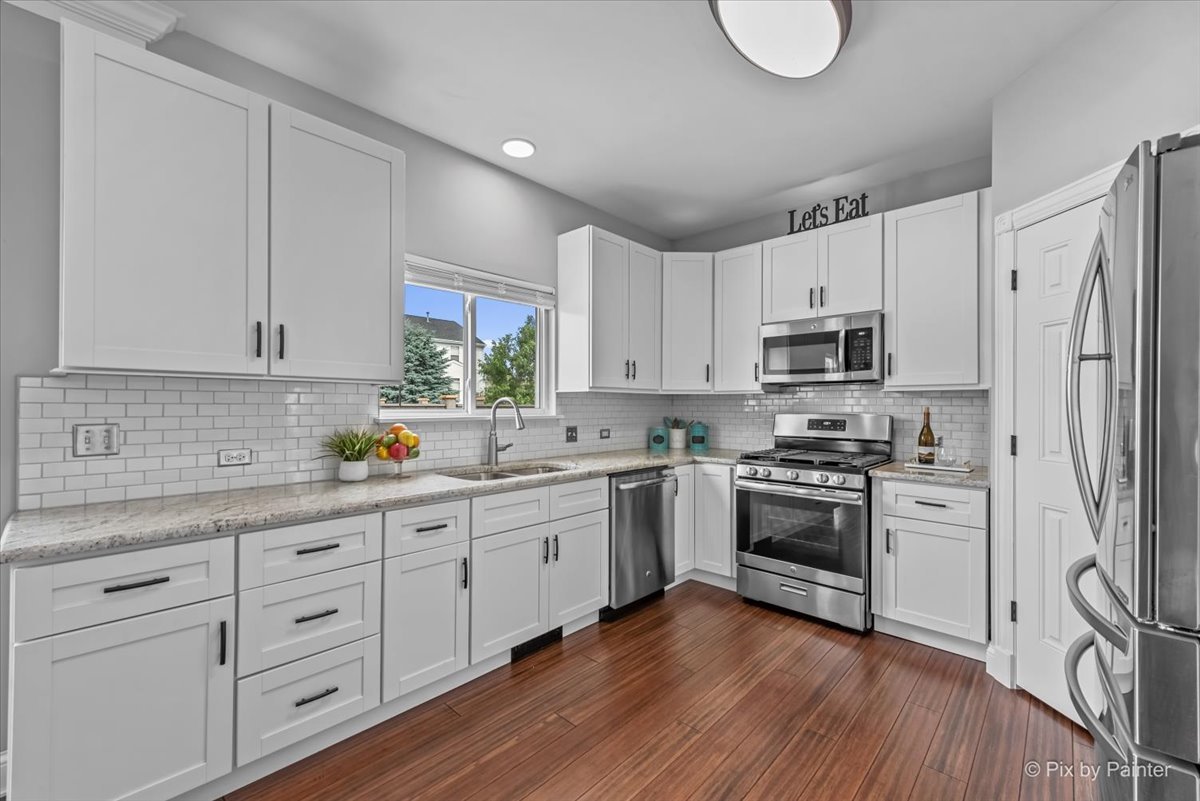 313 Market Street Genoa, IL 60135 - Photo 16 of 49 a kitchen with stainless steel appliances granite countertop a stove a sink dishwasher and a refrigerator with wooden floors