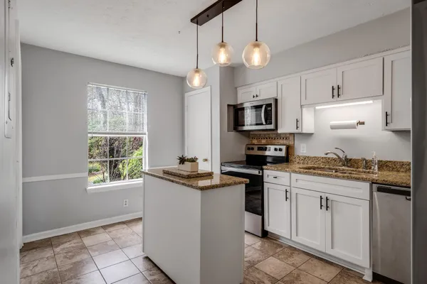 a kitchen with granite countertop a stove sink and microwave