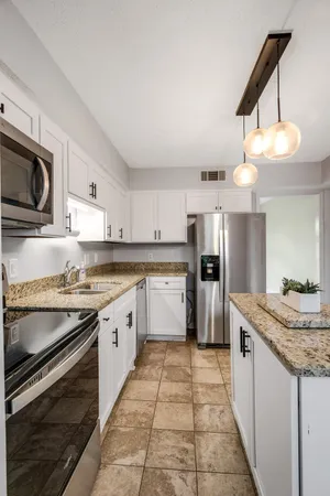 a large kitchen with granite countertop a stove top oven microwave and cabinets