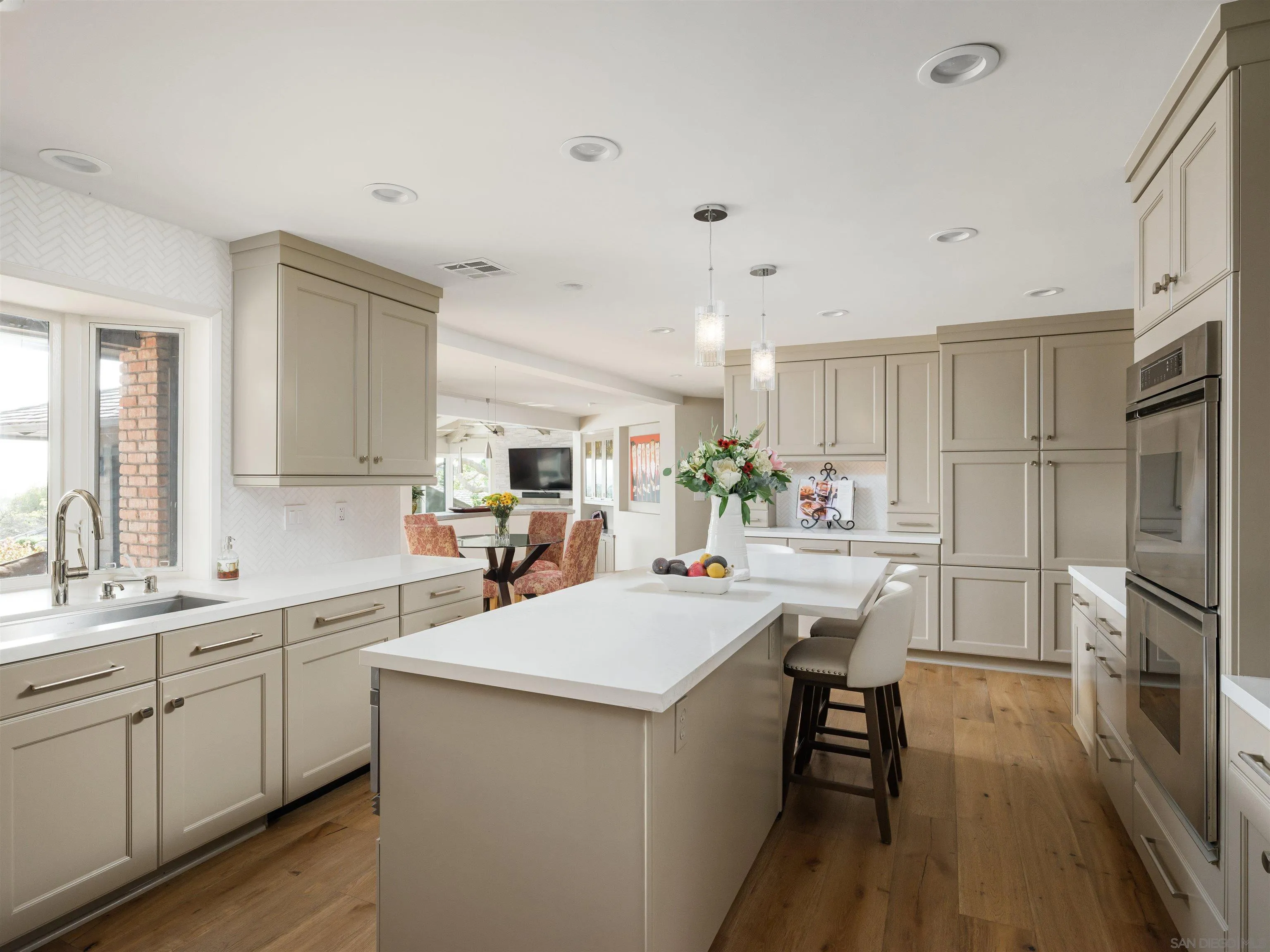 17136 El Mirador Rancho Santa Fe, CA 92067 - Photo 24 of 58 a kitchen with a sink a stove a refrigerator and white cabinets with wooden floor