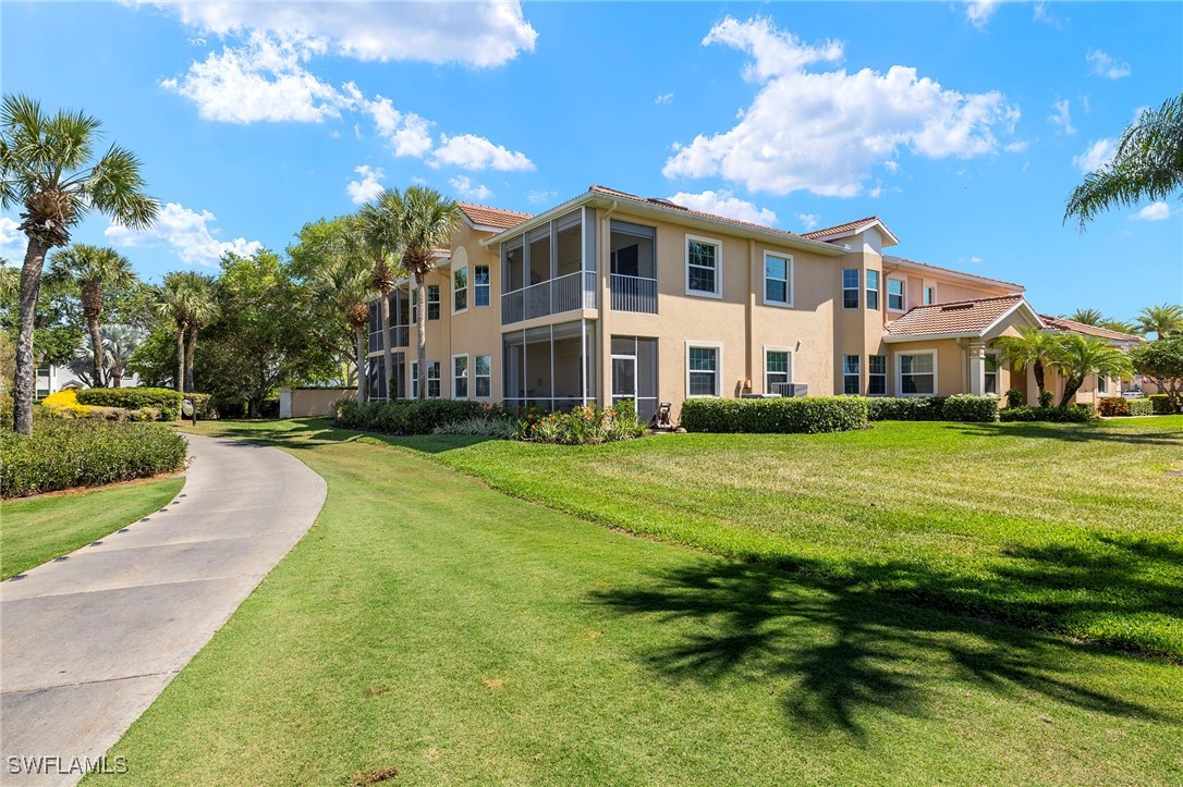 6035 Trophy Drive, Unit 103 Naples, FL 34110 - Photo 32 of 44 a view of a white house with a big yard and potted plants and large trees