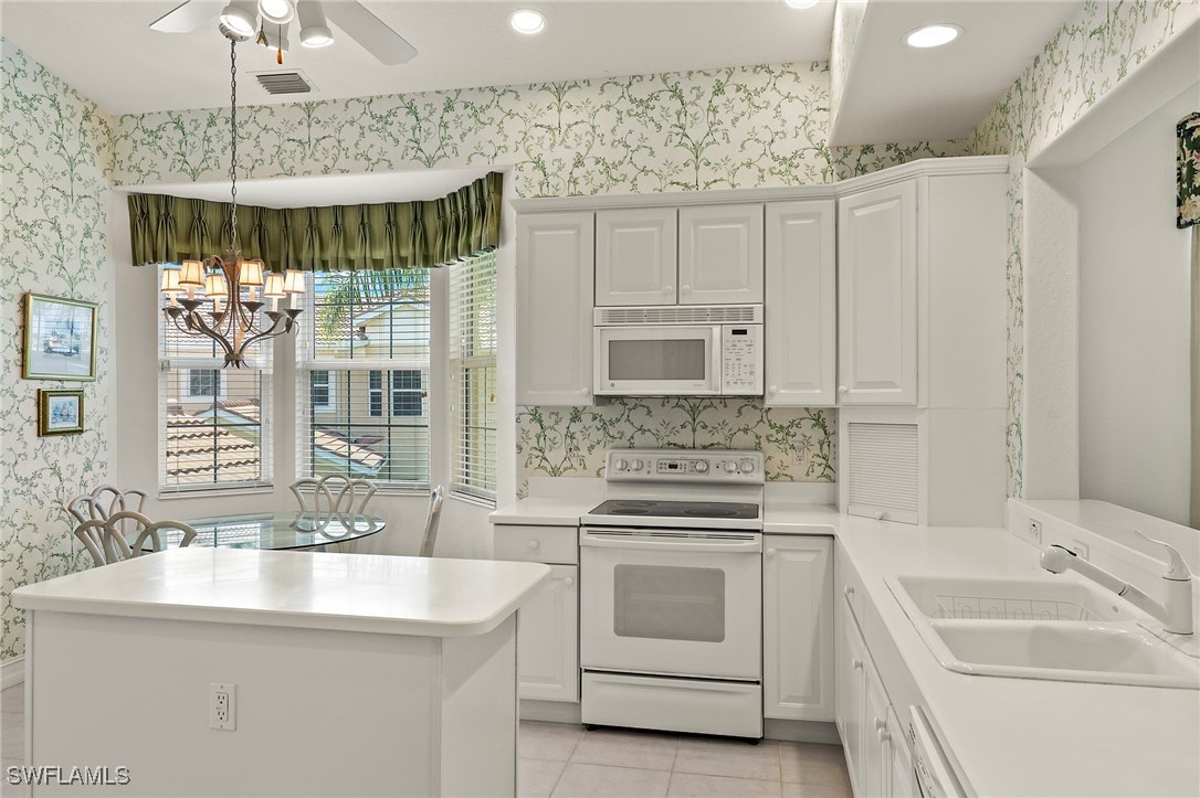 6035 Trophy Drive, Unit 103 Naples, FL 34110 - Photo 9 of 44 a kitchen with white cabinets and white appliances