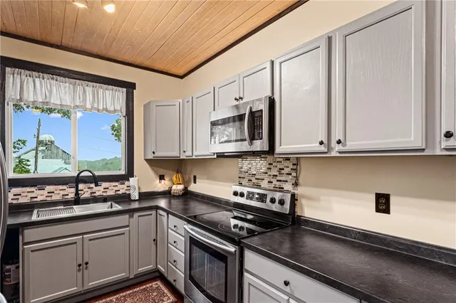 a kitchen with stainless steel appliances granite countertop a stove a sink and white cabinets