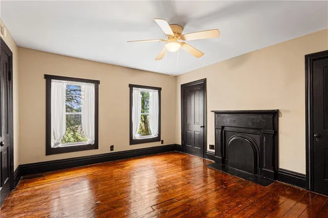 a view of an empty room with wooden floor fireplace and a window