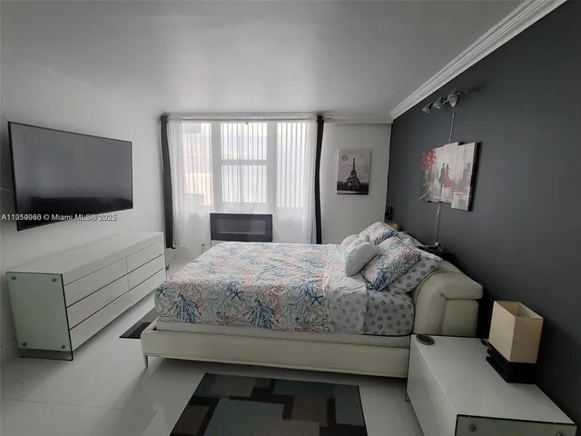 a bedroom with a bed and a flat tv screen on the dresser