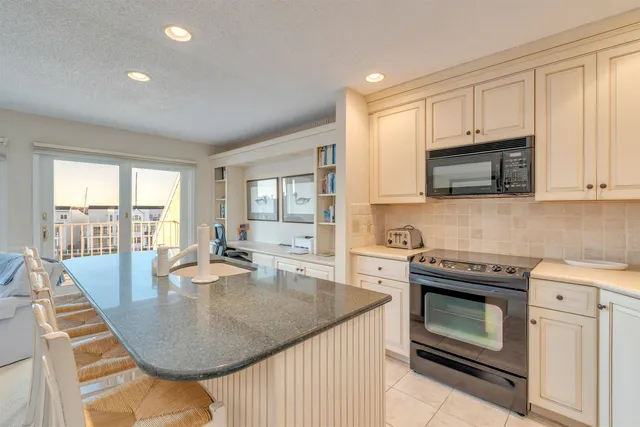 a kitchen with kitchen island granite countertop a stove a sink a dining table and chairs