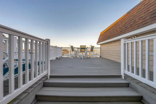 a view of a roof deck with table and chairs a barbeque with wooden floor