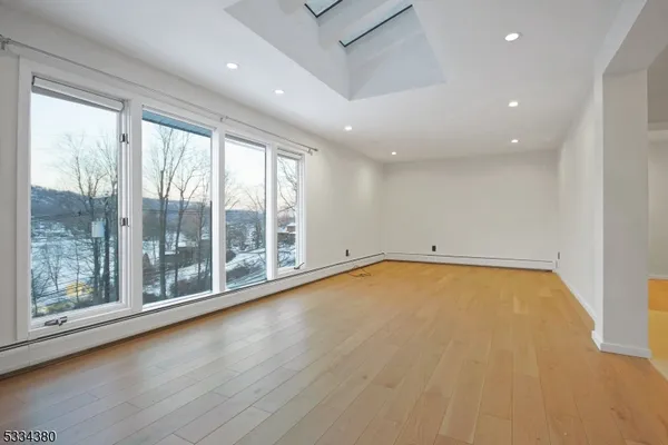 a view of empty room with wooden floor and fan