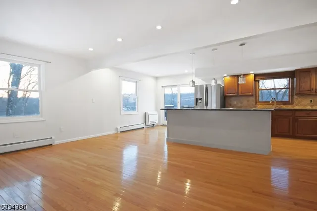 a large kitchen with stainless steel appliances granite countertop a large counter top and a wooden floors