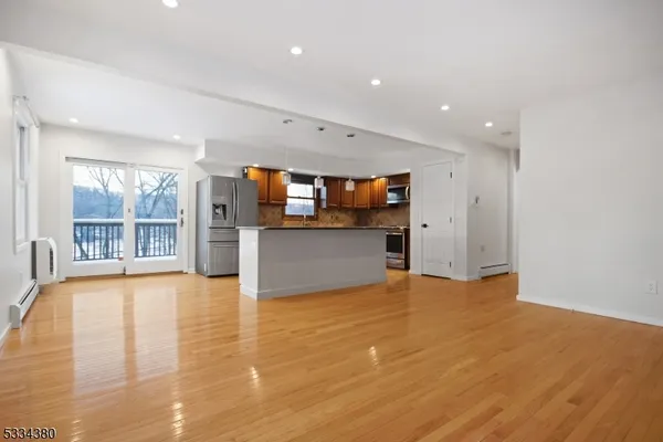 a view of an empty room with a window and kitchen view
