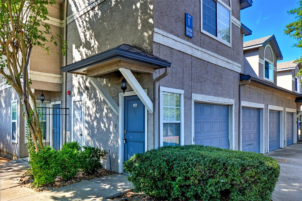 Property entrance with stucco siding, a garage, and driveway