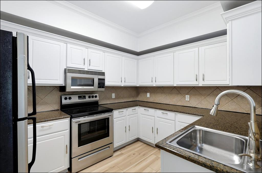 2601 Preston Road, Unit 1201 Plano, TX 75093 - Photo 21 of 31 Kitchen featuring appliances with stainless steel finishes, white cabinets, crown molding, and decorative backsplash