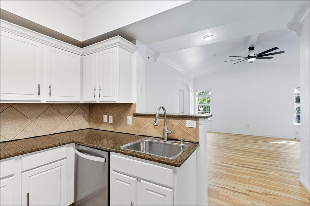 2601 Preston Road, Unit 1201 Plano, TX 75093 - Photo 22 of 31 Kitchen featuring tasteful backsplash, white cabinets, light wood finished floors, stainless steel dishwasher, and lofted ceiling