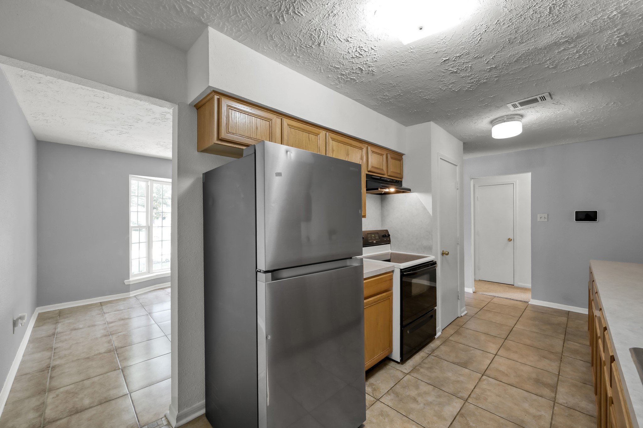 4314 Enchantedgate Drive Spring, TX 77373 - Photo 14 of 47 Kitchen features modern appliances, ample cabinet space, and tiled flooring. It opens into a bright dining area with large windows, offering a cozy, well-lit space for meals.