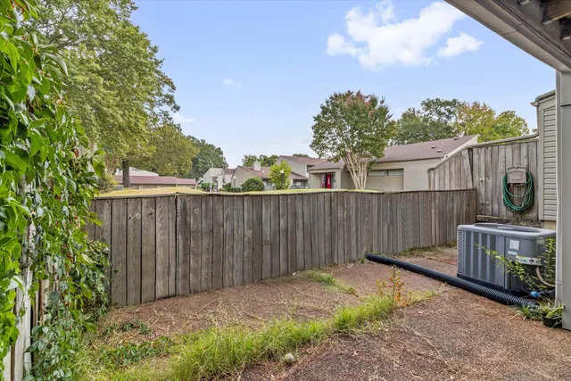 a view of a backyard with wooden fence and trees