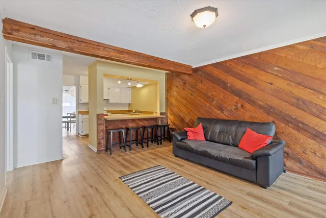 a living room with furniture and a dining table with wooden floor