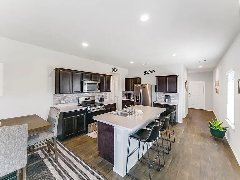 2406 High Spruce Circle Spring, TX 77373 - Photo 8 of 32 a kitchen with stainless steel appliances granite countertop a stove top oven a sink a dining table and chairs