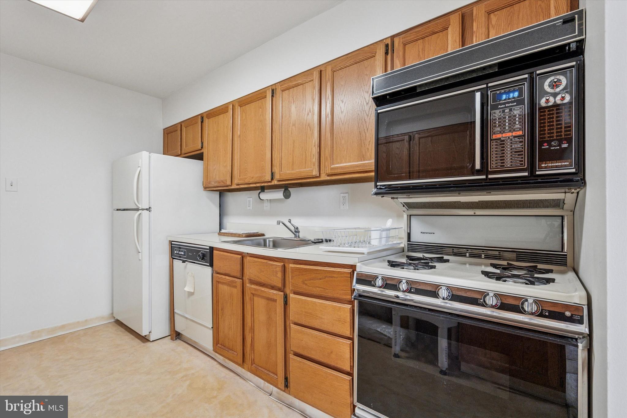 3900 West Ford Road, Unit 15C Philadelphia, PA 19131 - Photo 5 of 15 a kitchen with stainless steel appliances granite countertop a stove microwave and refrigerator