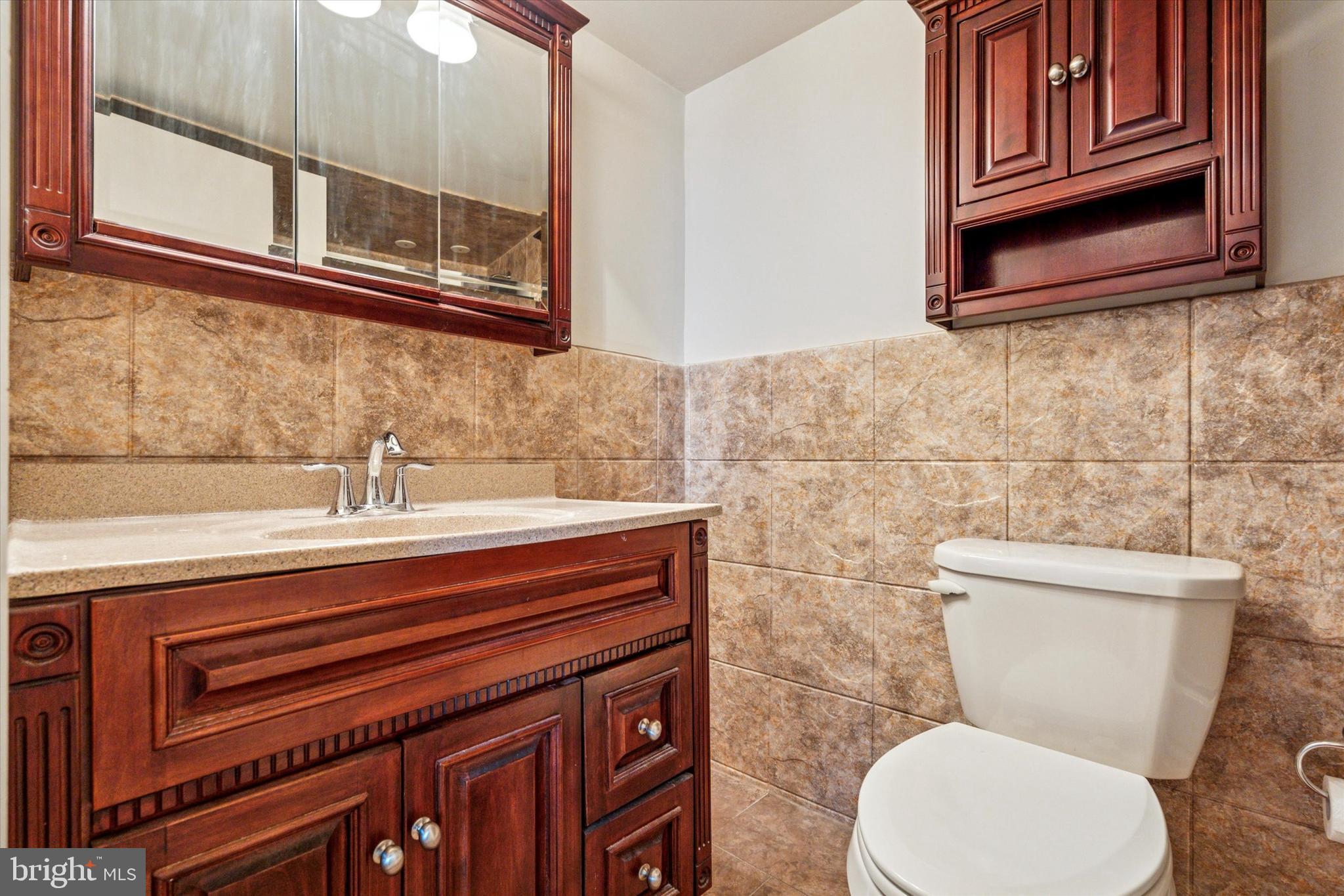 3900 West Ford Road, Unit 15C Philadelphia, PA 19131 - Photo 10 of 15 a bathroom with a toilet a sink and mirror