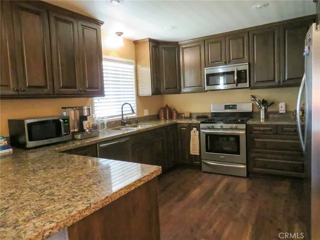 a kitchen with stainless steel appliances granite countertop a stove a sink and a microwave