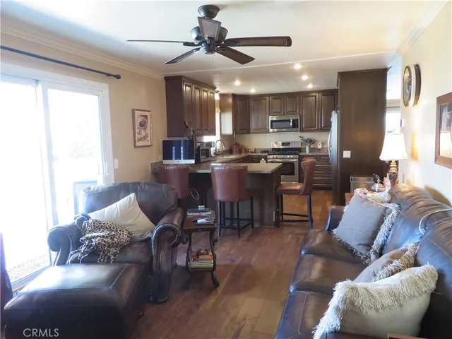 a living room with furniture kitchen area and a wooden floor