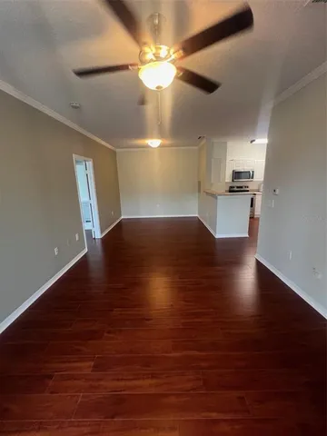 a view of kitchen and empty room with wooden floor