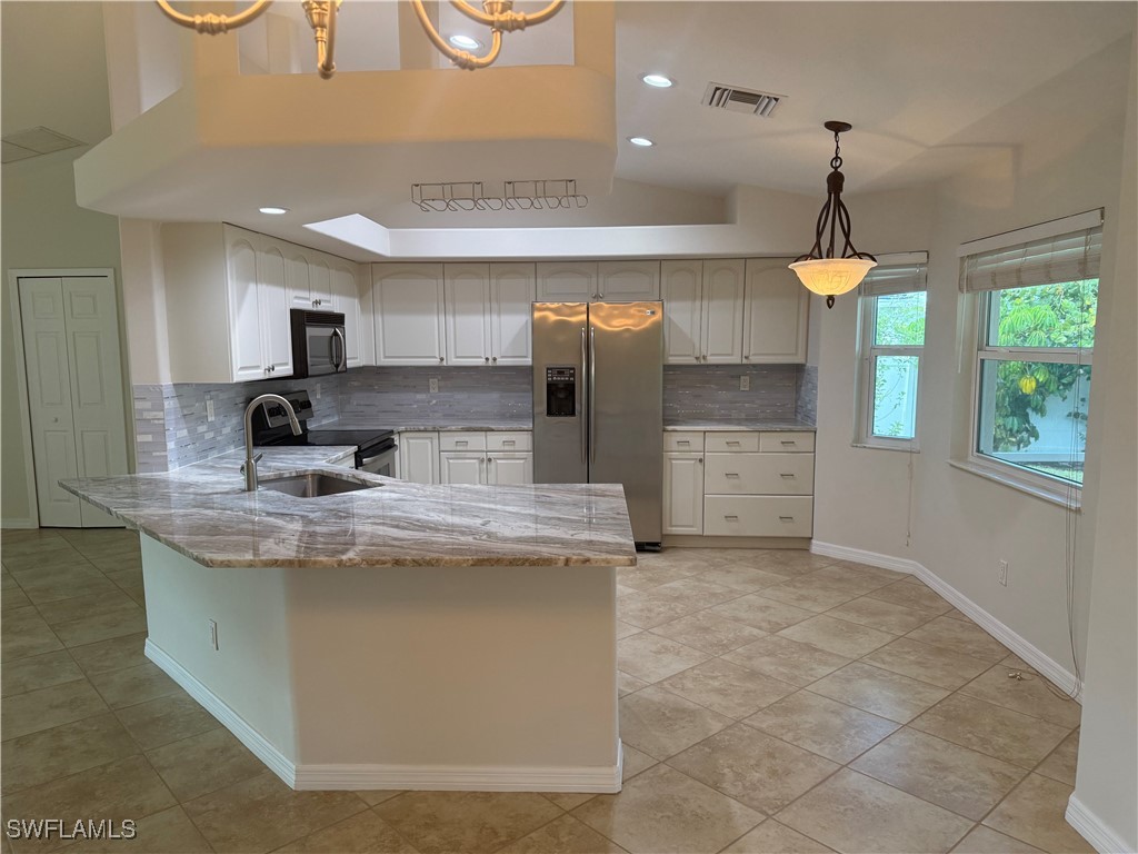 18249 Oak Road Fort Myers, FL 33967 - Photo 5 of 16 a kitchen with kitchen island granite countertop a stove a sink a refrigerator and a fireplace