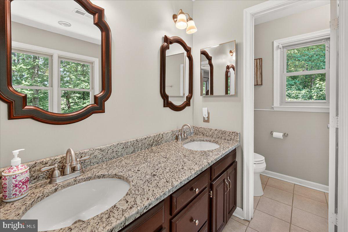 10490 Lakeridge Court New Market, MD 21774 - Photo 32 of 79 a bathroom with a granite countertop toilet a sink and a large mirror