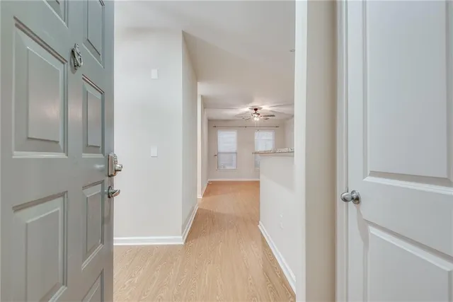 a view of a hallway with wooden floor and a bathroom
