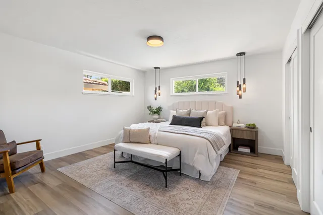 a view of a hallway with wooden floor and a bathroom
