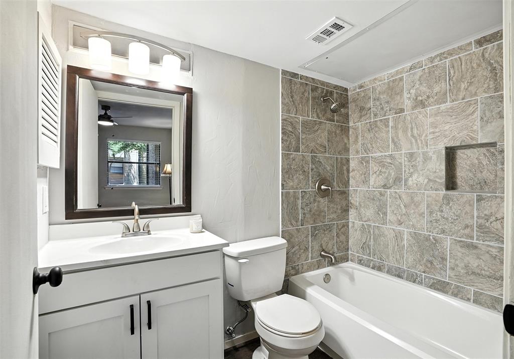 3022 Forest Lane, Unit 308 Dallas, TX 75234 - Photo 14 of 21 a bathroom with a bathtub shower sink vanity mirror and toilet