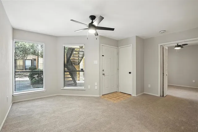a living room with a ceiling fan and a rug